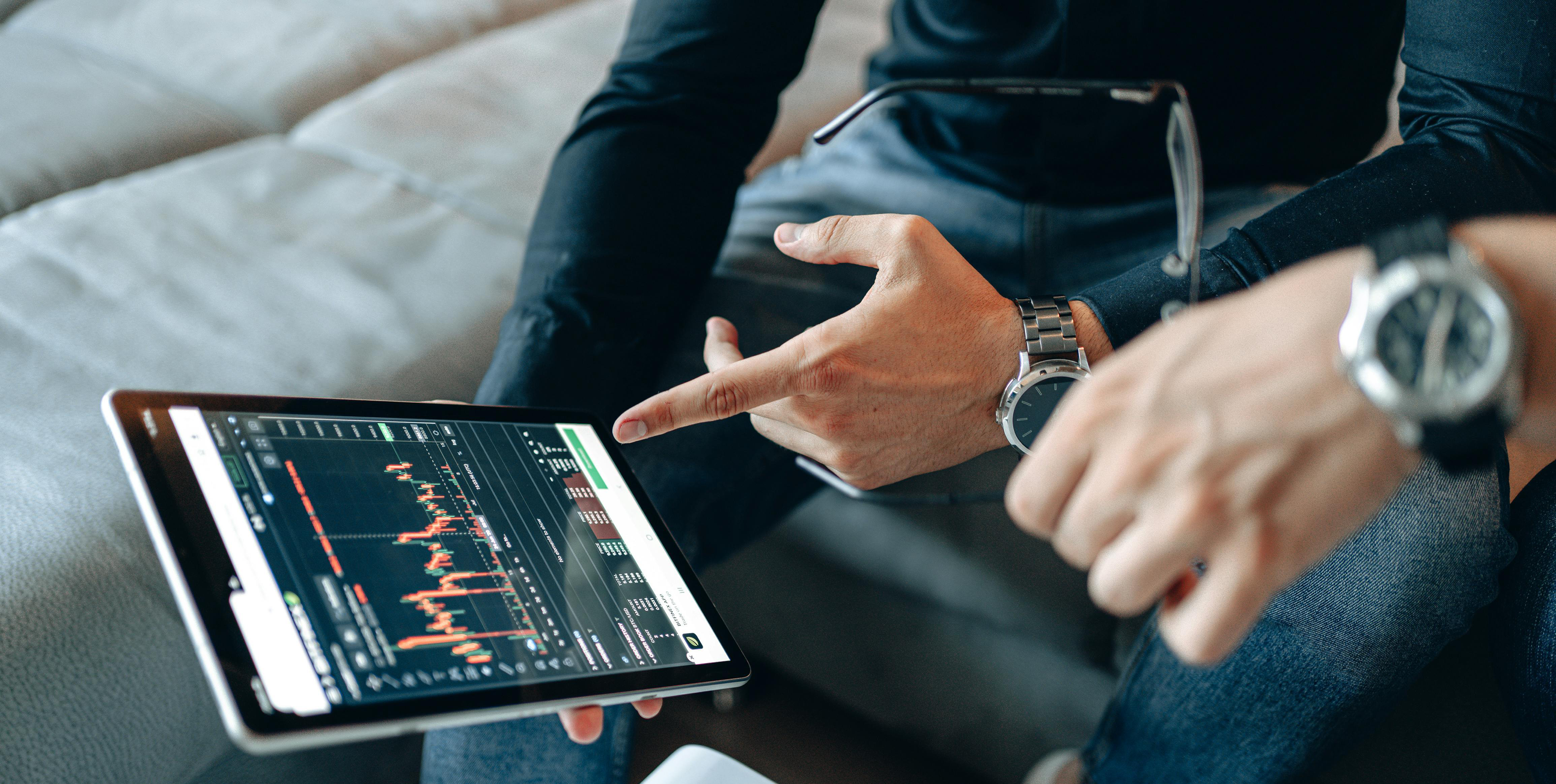 Homem sentado em sofÃ¡ a analisar grÃ¡fico de investimento em tablet