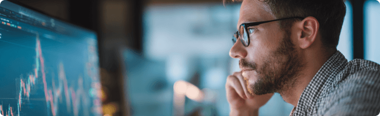 Egy koncentrÃ¡lt kereskedÅ Ã©lÅ Ã¡rfolyamgrafikonokat figyel a szÃ¡mÃ­tÃ³gÃ©p kÃ©pernyÅjÃ©n.