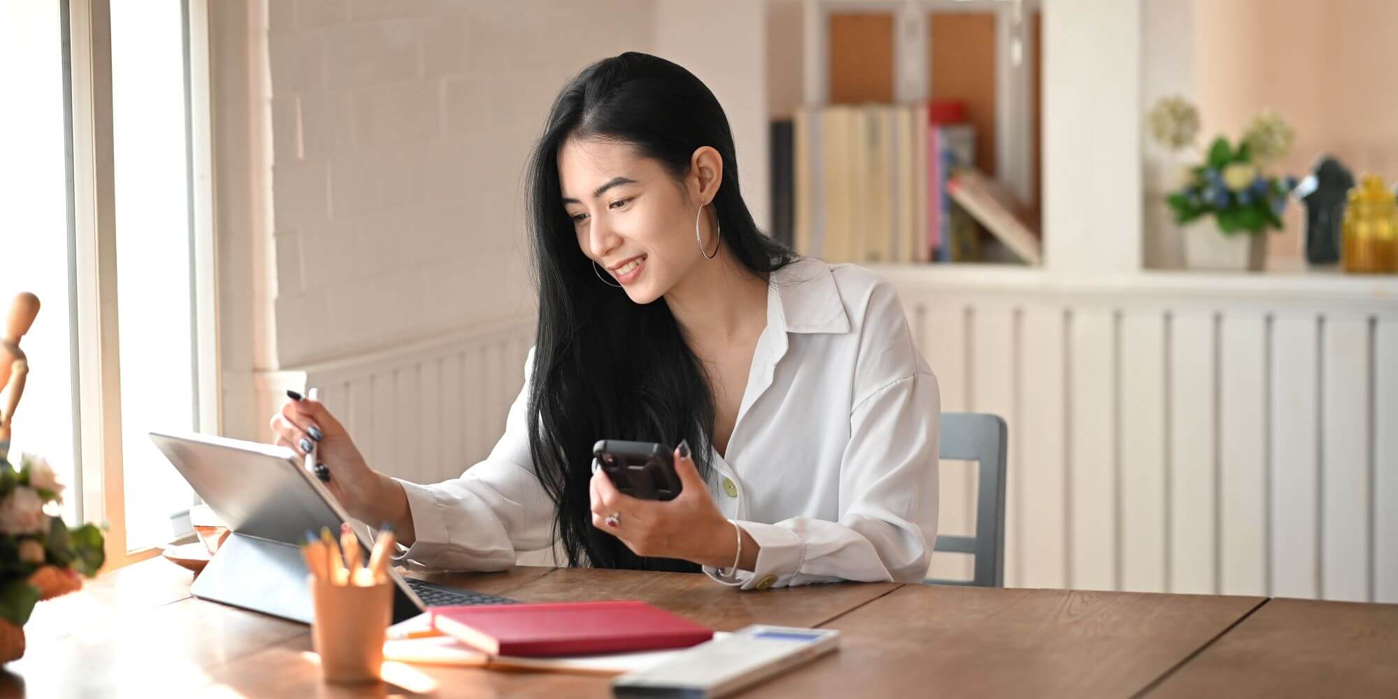 Imagen de una chica con un telÃ©fono mÃ³vil frente a una tablet en un artÃ­culo sobre quÃ© son las opciones financieras