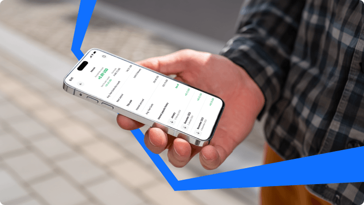 Egy kÃ©z okostelefont tart, amelyen egy portfÃ³liÃ³ kÃ©pernyÅje lÃ¡thatÃ³ piaci adatokkal Ã©s szÃ¡mlateljesÃ­tmÃ©nnyel, aktÃ­v befektetÃ©shez Ã©s kereskedÃ©shez