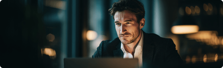 FÃ©rfi dolgozik laptopon egy fÃ©lhomÃ¡lyos irodÃ¡ban, pÃ©nzÃ¼gyi adatokat vagy piaci trendeket elemez.