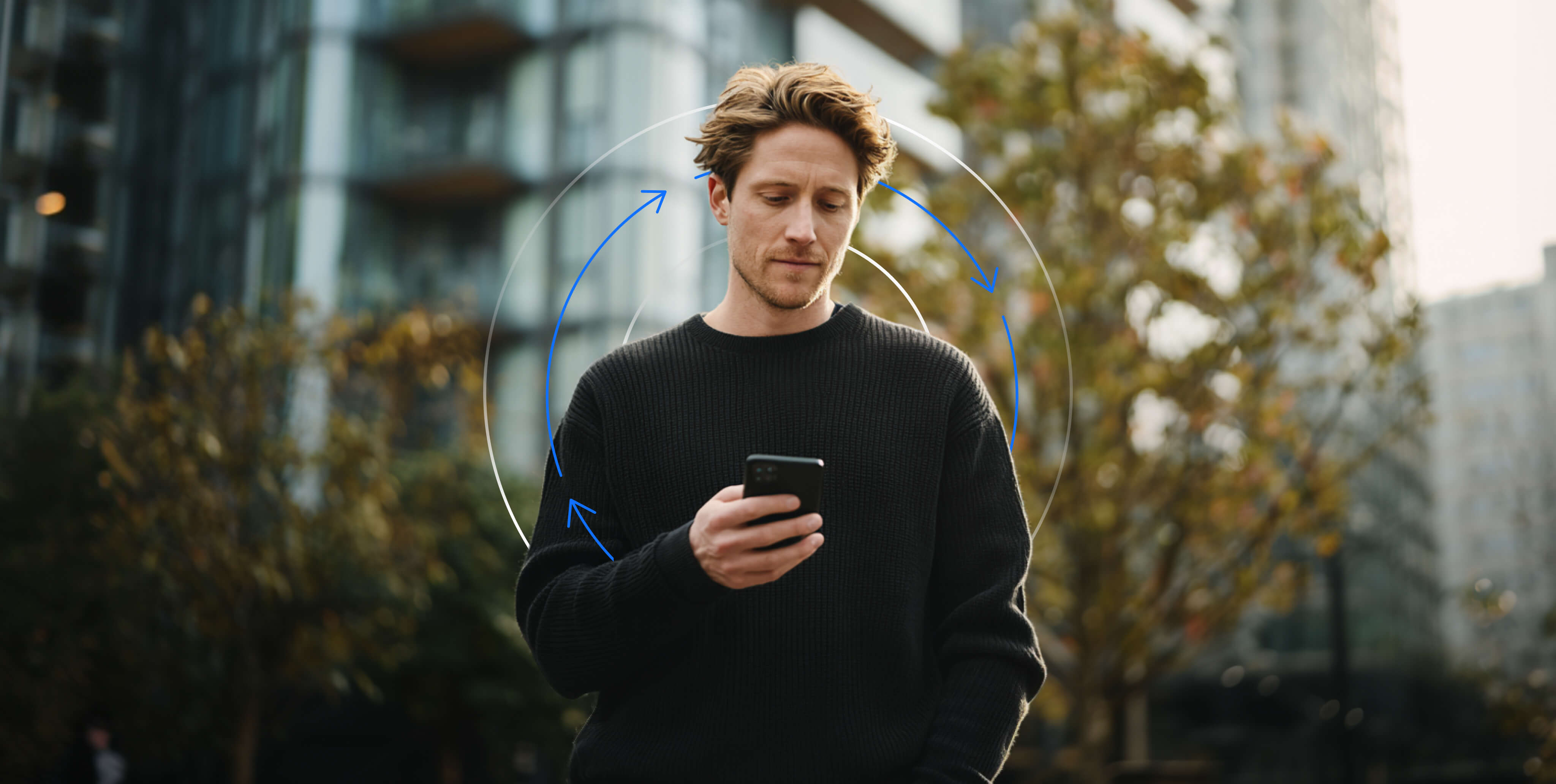 Szabadban Ã¡llÃ³ fÃ©rfi okostelefont nÃ©z, kÃ¶rkÃ¶rÃ¶s grafikus nyilakkal, amelyek a gazdasÃ¡gi vagy piaci ciklusokat szimbolizÃ¡ljÃ¡k.