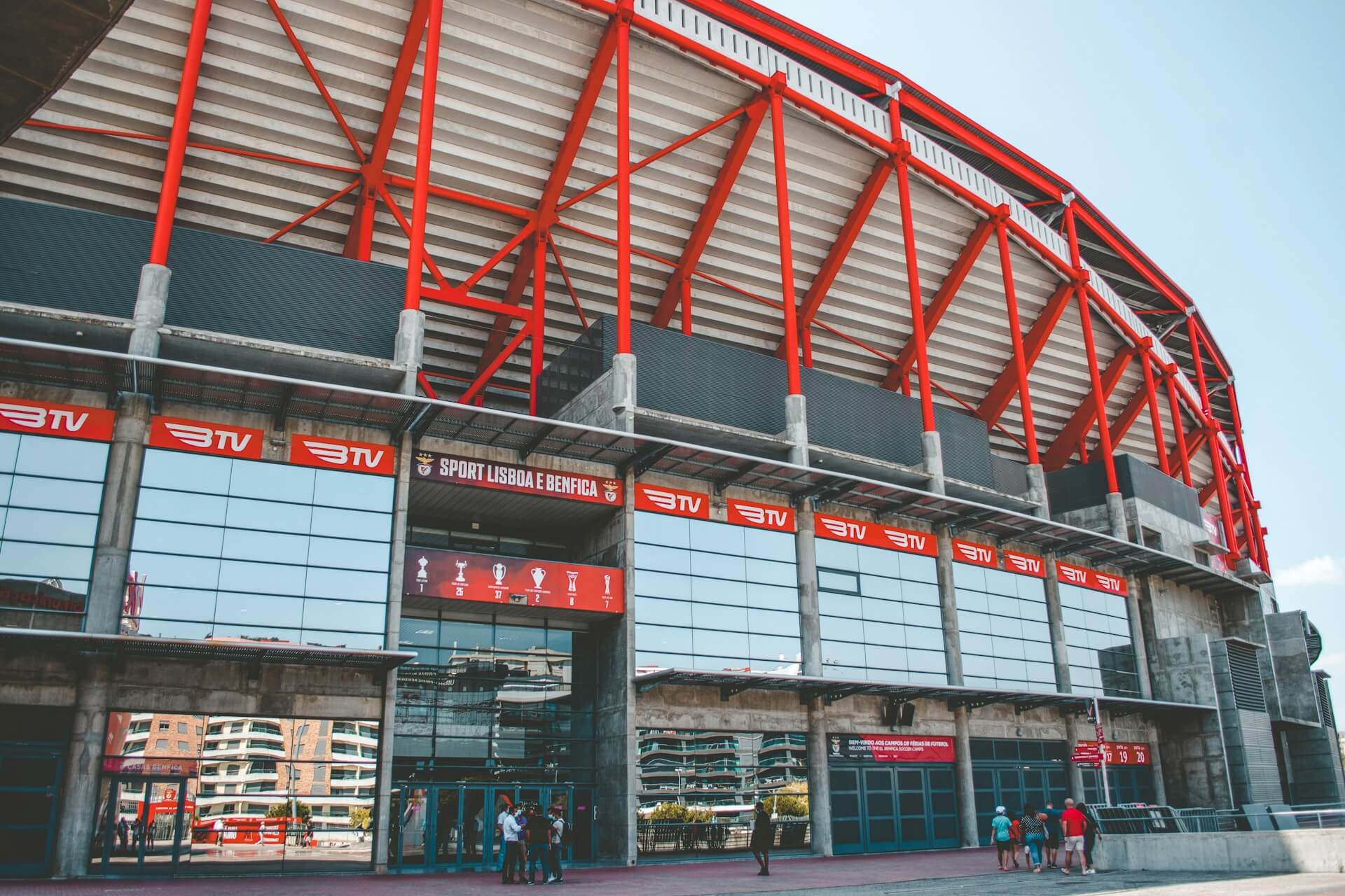 Entrada do EstÃ¡dio da Luz Ã  luz do dia com alguns adeptos na porta