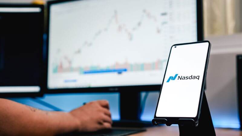 Imagen de un inversor frente a un ordenador en el que se lee Nasdaq 100