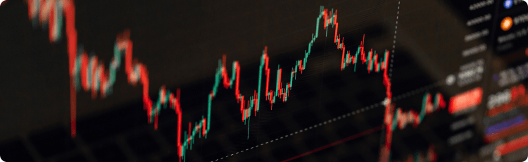 Close-up grafik keuangan dengan candlestick merah dan hijau yang menunjukkan volatilitas harga dan tren pasar.