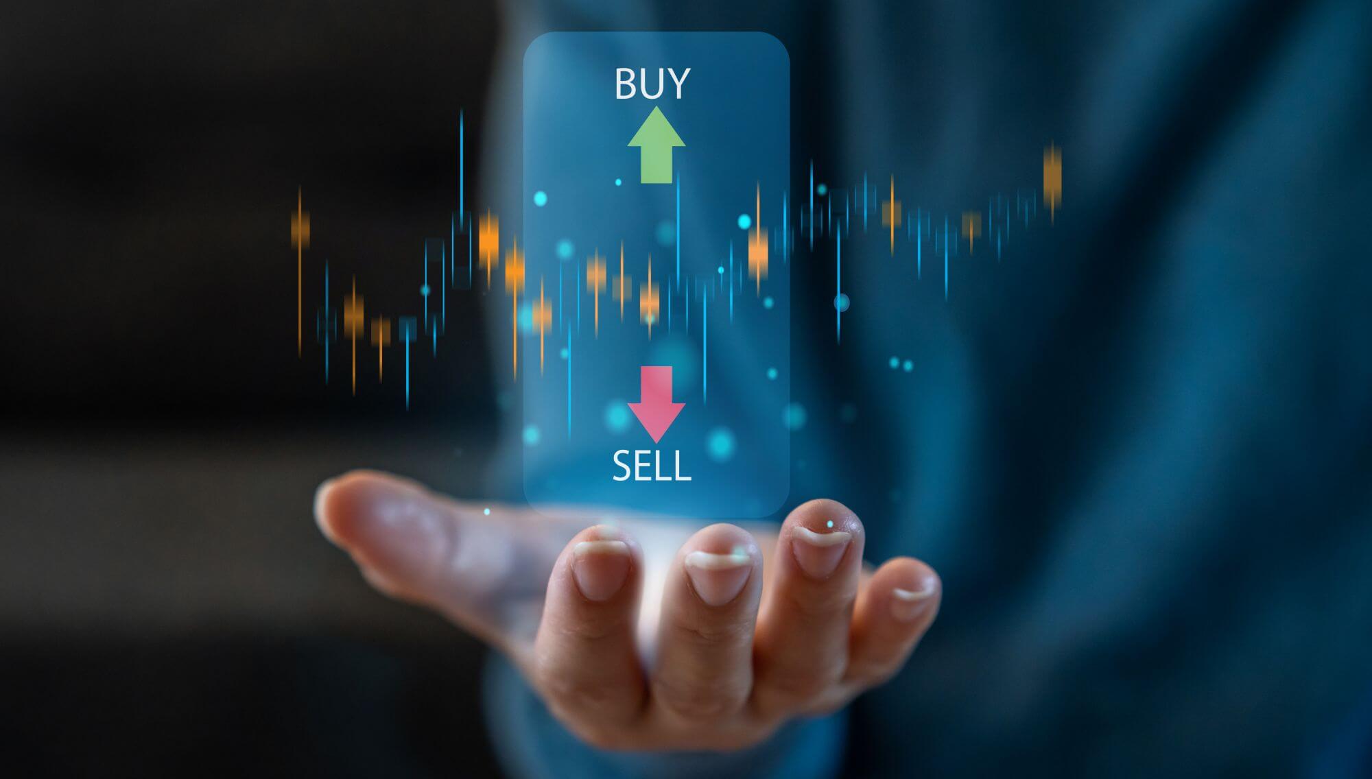 Imagen de la mano de un inversor sobre la que se leen las palabras buy y sell en un artÃ­culo sobre cuÃ¡ndo vender acciones