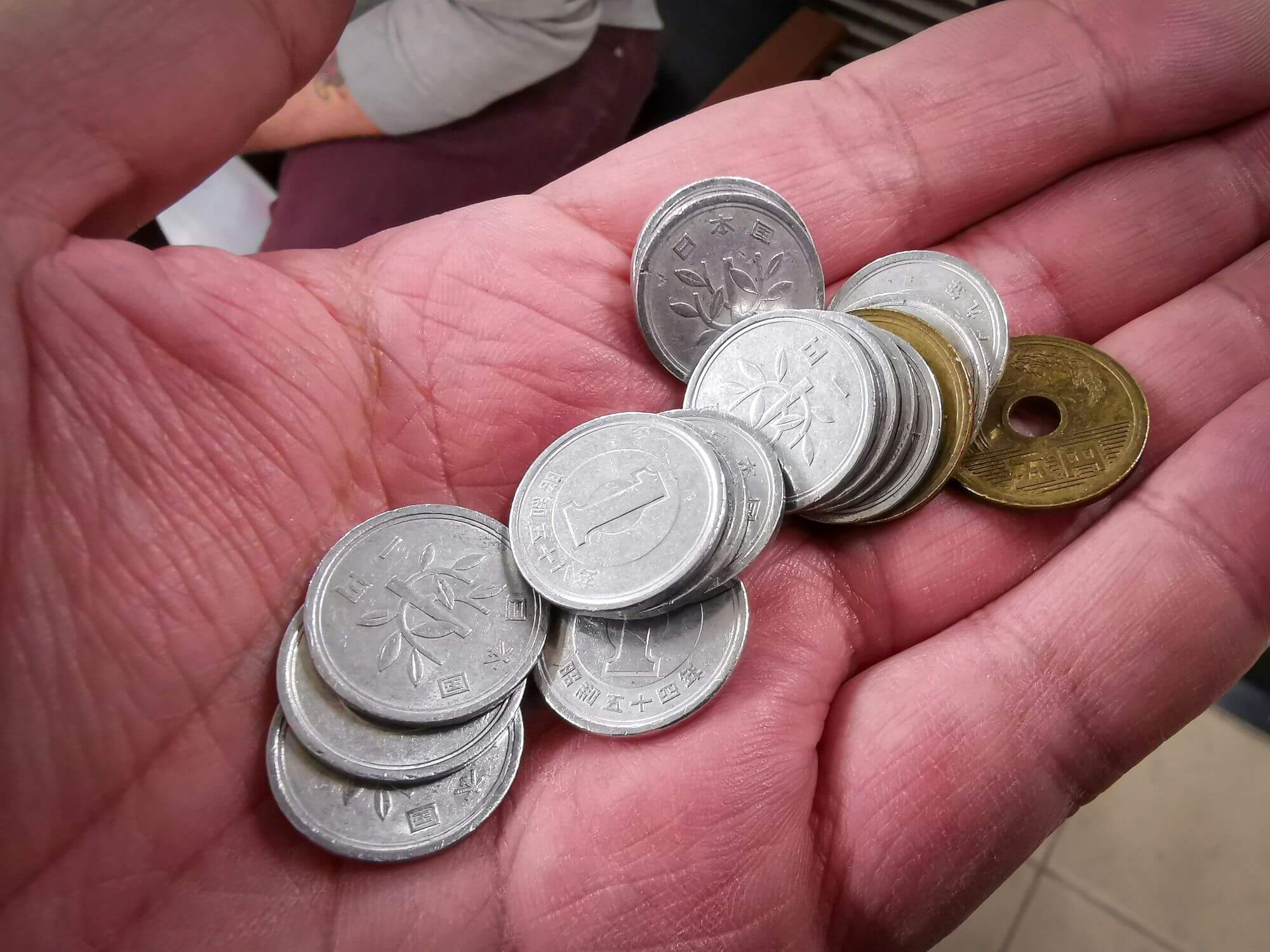 Imagen de una mano sosteniendo monedas de yenes