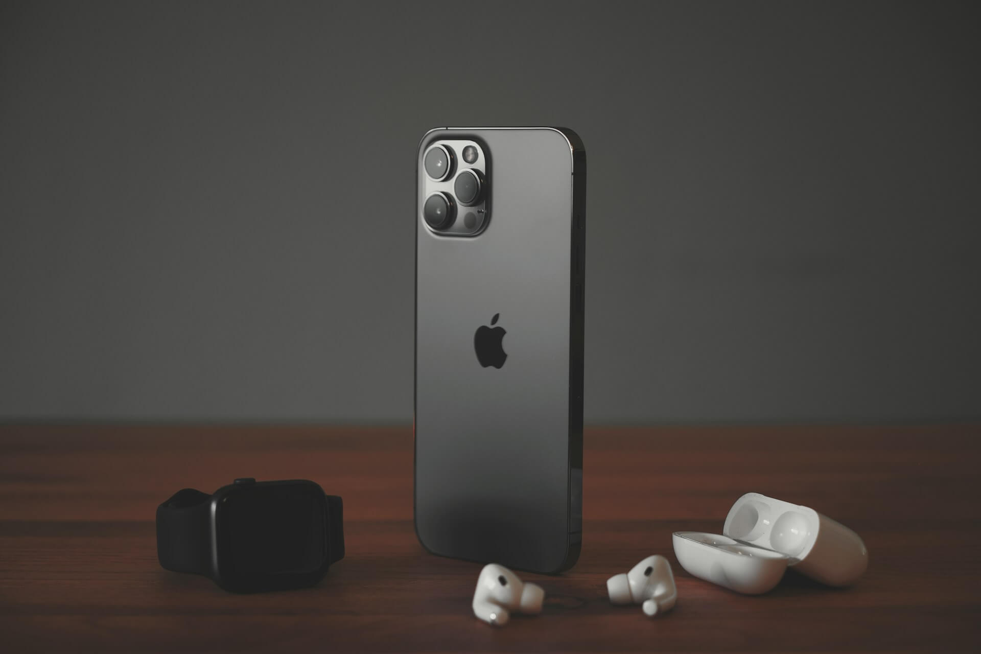 Iphone preto ao lado de Apple Watch e Airpods 
