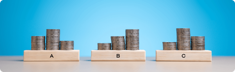 Tri stohy mincí s písmenami „abc“ umiestnenými na vrchu, symbolizujúce finančný rast a finančnú gramotnosť