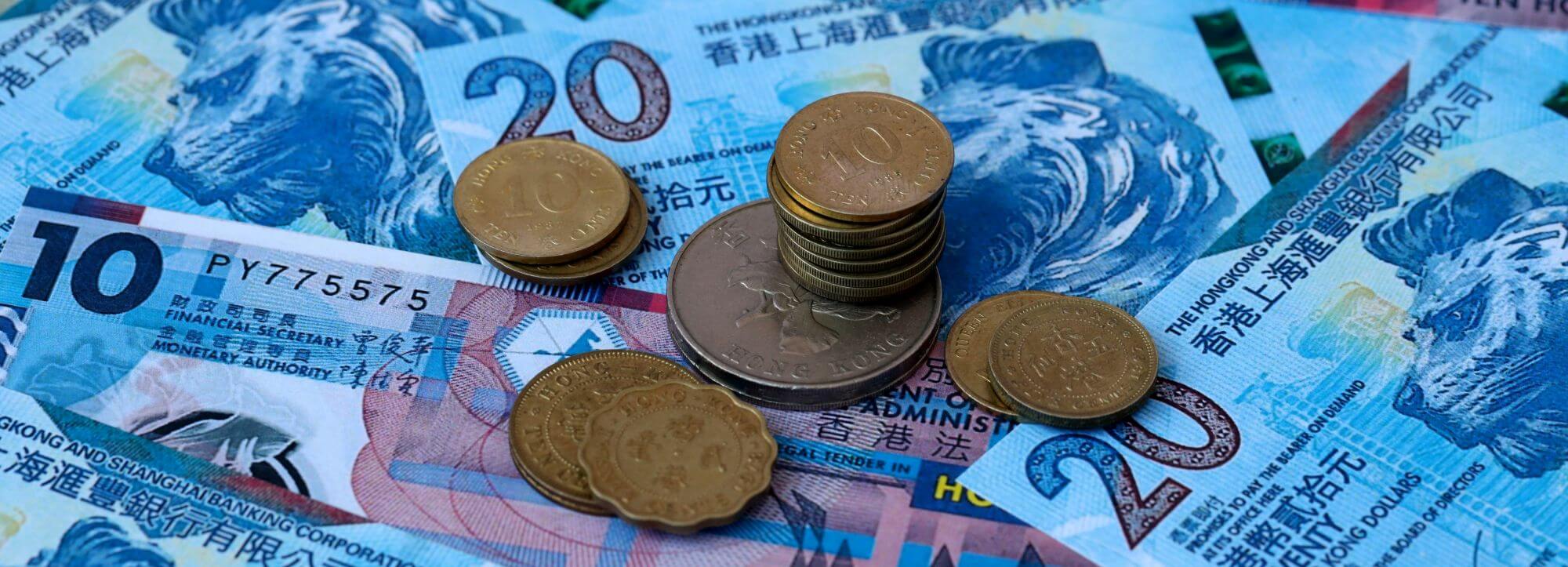 Imagen de un conjunto de monedas sobre un conjunto de billetes en un artículo sobre qué es el spread en Bolsa