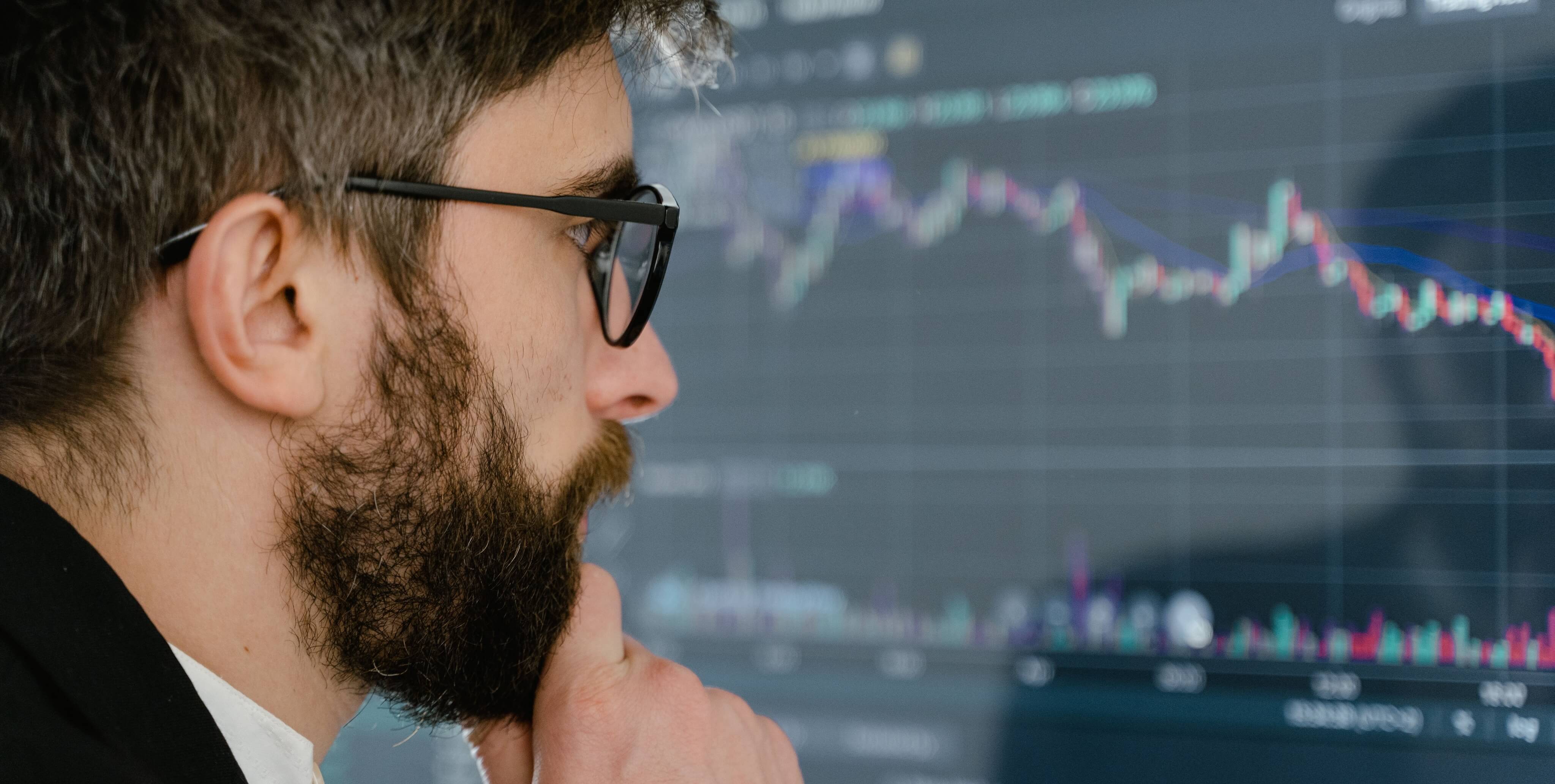 Investidor sério a analisar gráfico de investimentos em ecrã