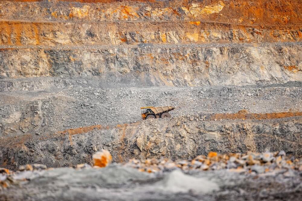 Operaciones de mineria de Industrial de Anuncio con grandes camiones pesados amarillos en mina a cielo abierto de oro, cobre, mineral de hierro.