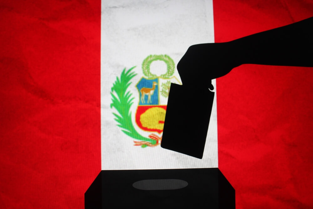 Silueta de una mano emitiendo un voto frente a la bandera de PerÃº.
