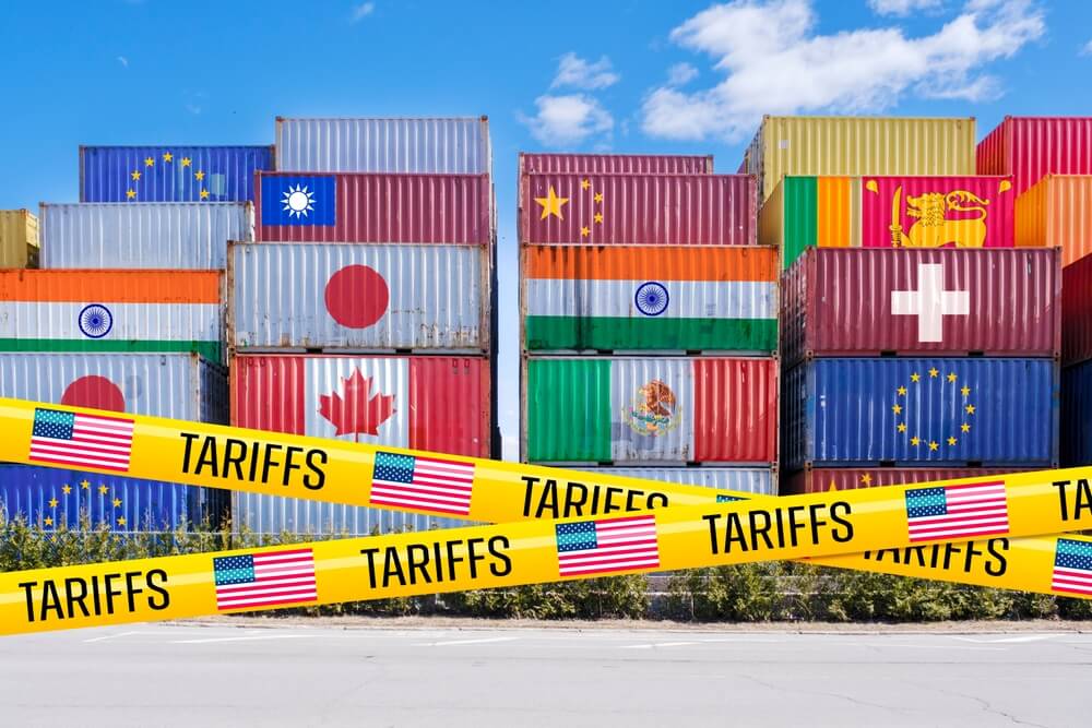 Contenedores de envÃ­o adornados con banderas de todo el mundo, bloqueados con cinta de aranceles estadounidenses.