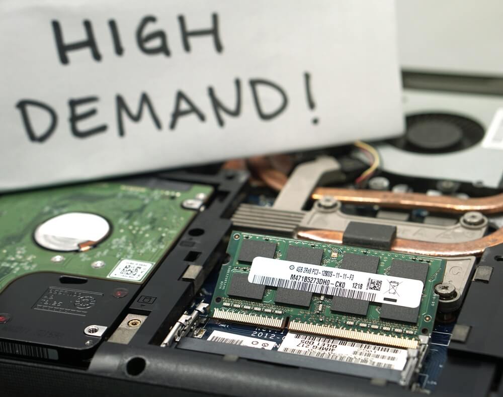 Interior de un portátil con un letrero de "Alta demanda" detrás de los componentes de RAM y HDD.