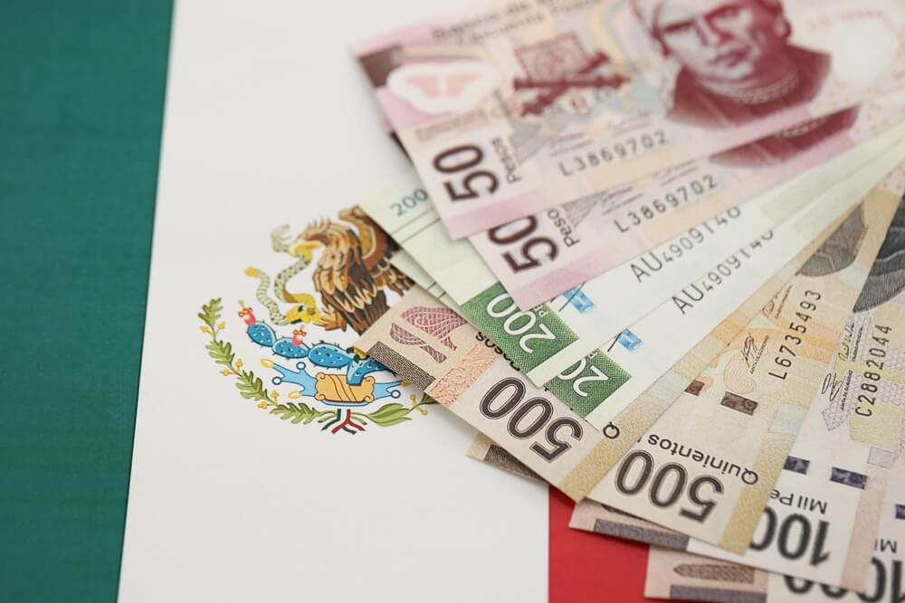 Billetes de peso mexicano con la bandera de mexico al fondo
